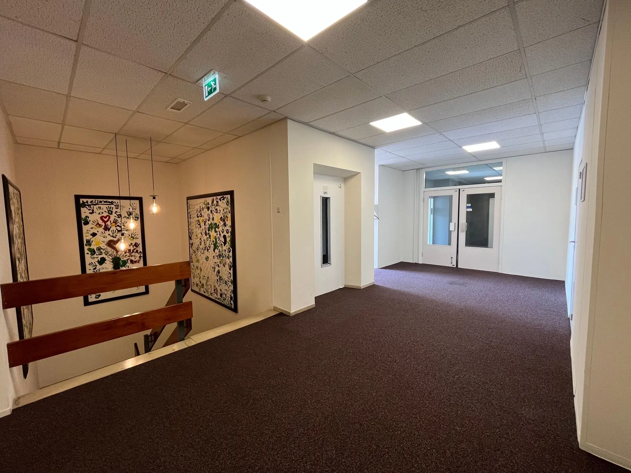 Gang in een kantoorpand aan de Jan van Eycklaan met kunst aan de muur, bruine vloerbedekking en witte deuren.